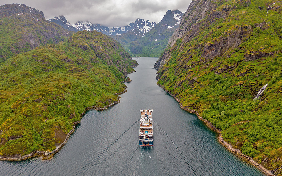 Cruise ship navigating stunning fjord landscape.