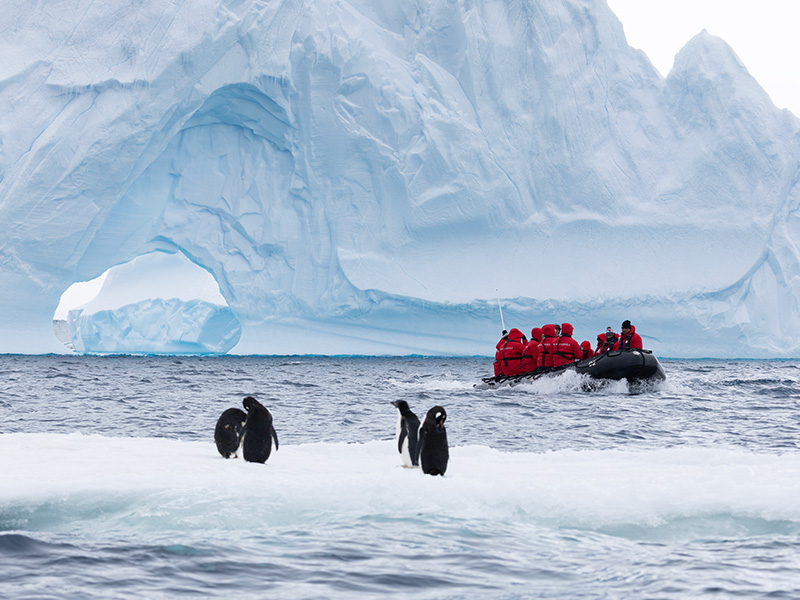 A Zodiac exploring Brown Bluff in Antarctica with penguins in the foreground