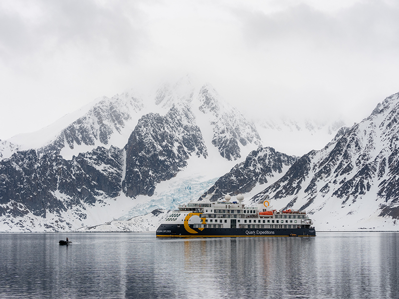 A cruise ship surrounded by snowy mountains in Spitsbergen